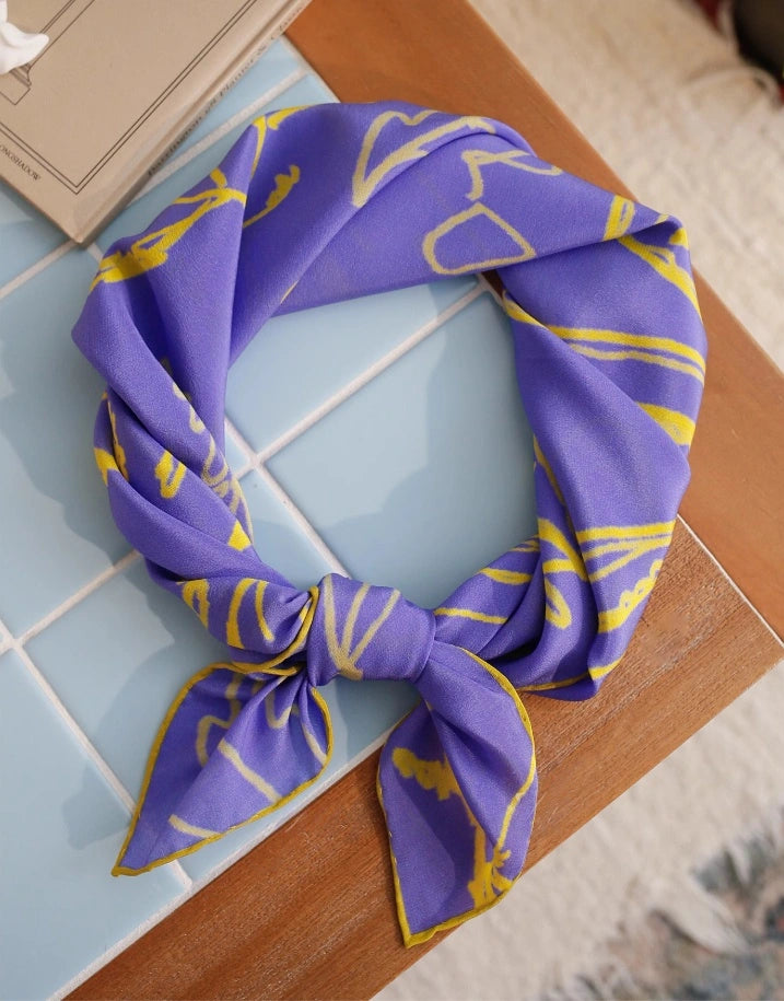Blue botanical silk square scarf styled creatively, showcasing its artistic design and luxurious feel.
