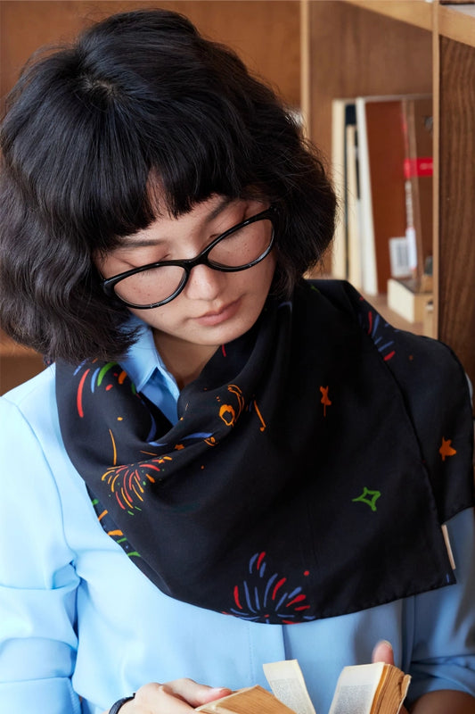 Fireworks Ballerina silk scarf in midnight black, styled as a neck scarf to emphasize its timeless elegance.
