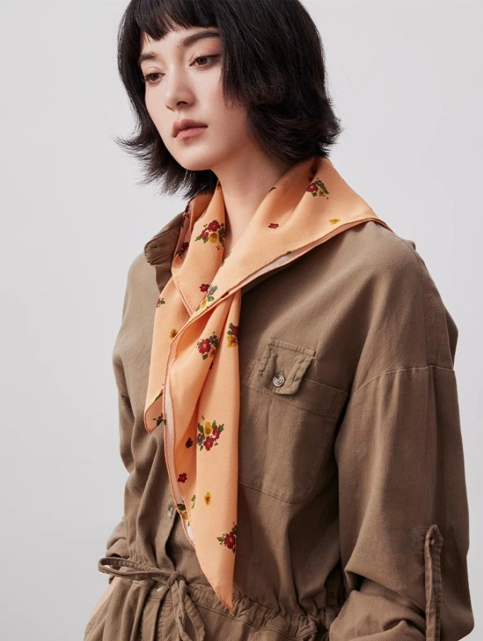 Light orange floral silk square scarf draped gracefully, showcasing smooth texture and timeless design.