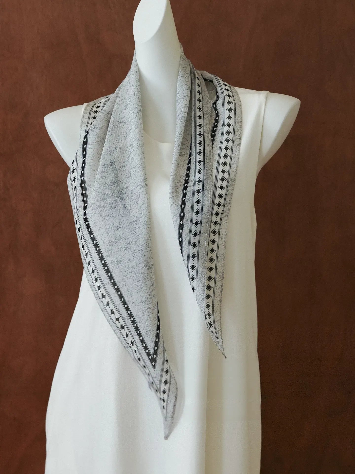 Black and gray geometric silk wool diamond scarf draped over a white mannequin