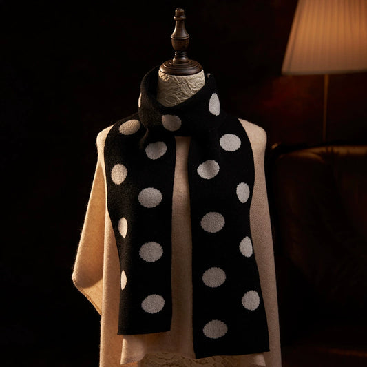 Black cashmere scarf with cream polka dots wrapped around a mannequin's neck, with both ends hanging down the front.