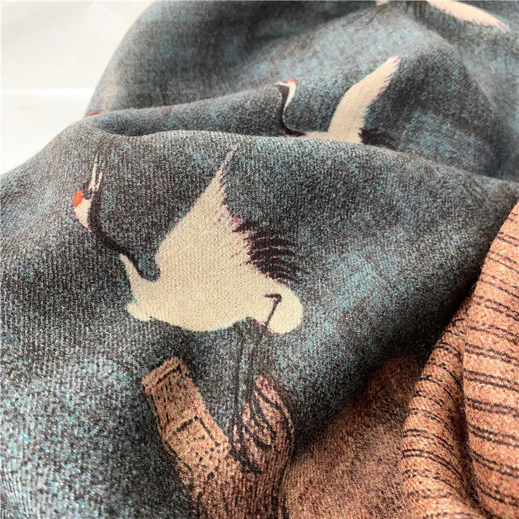 Macro detail of a white crane motif on the soft blue fine wool scarf