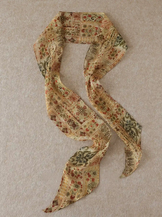 Long brown floral mulberry silk ribbon scarf displayed in a flowing S shape on a neutral beige background