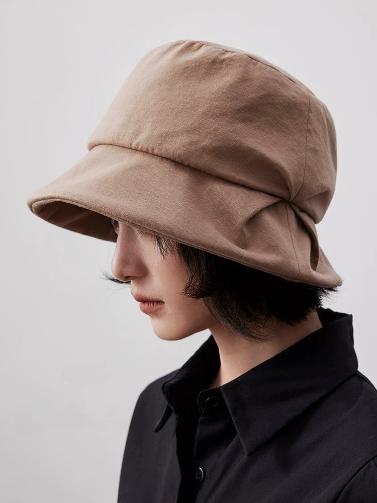 Close side view of a camel pleated bucket hat with a softly folded brim and sculpted crown