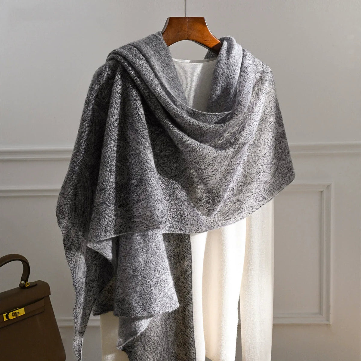 Charcoal grey cashmere scarf with a tonal paisley pattern draped over a cream knit top.