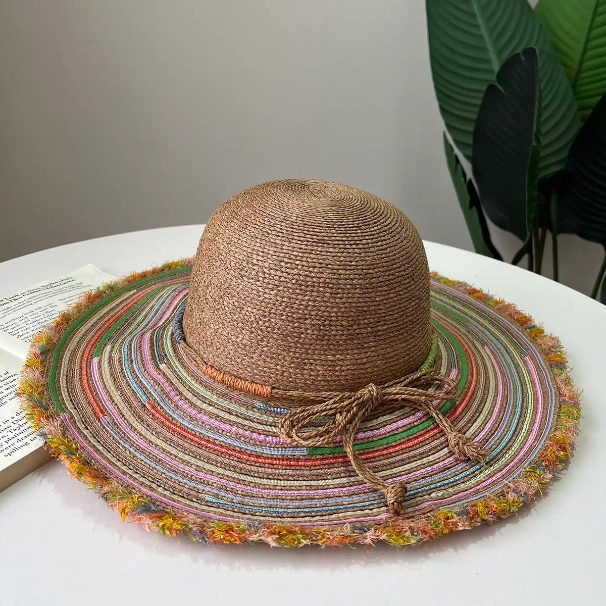 Warm brown raffia wide brim sun hat with colorful striped brim and boho frayed edge.