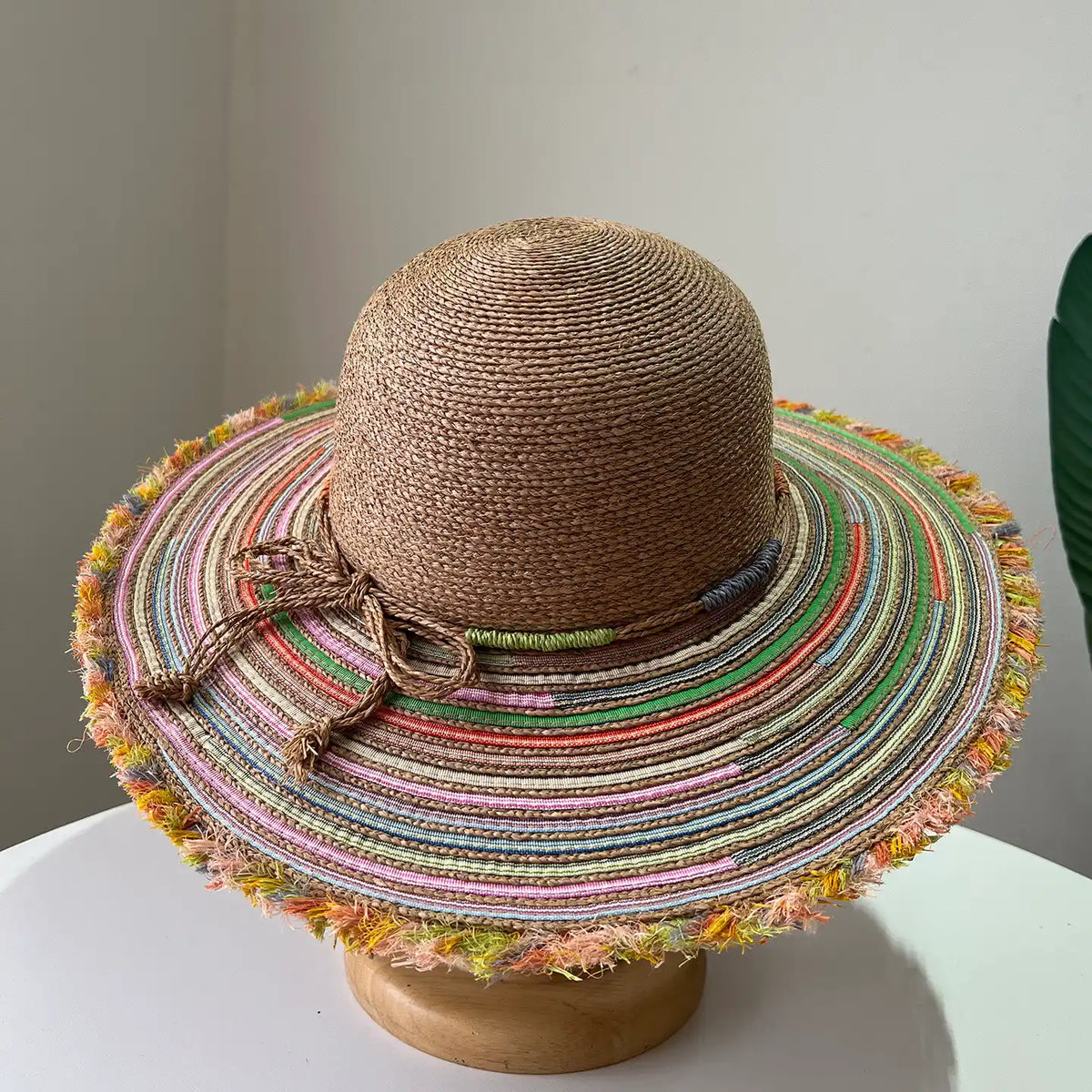 Brown raffia straw beach hat with multicolor woven brim and natural tie detail.