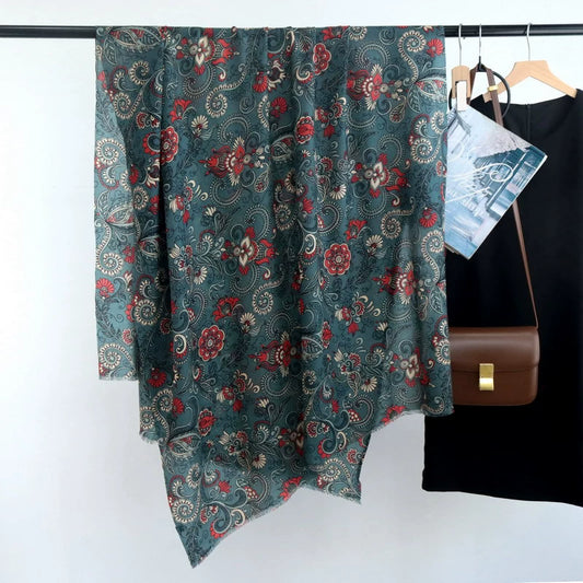 Dark green vintage paisley floral wool scarf displayed full length beside a black dress and brown handbag