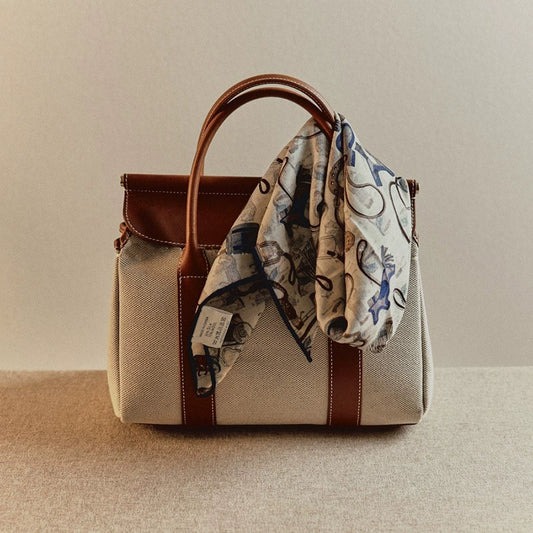 Square silk wool scarf tied on leather handle bag, horse tack accessories print detail