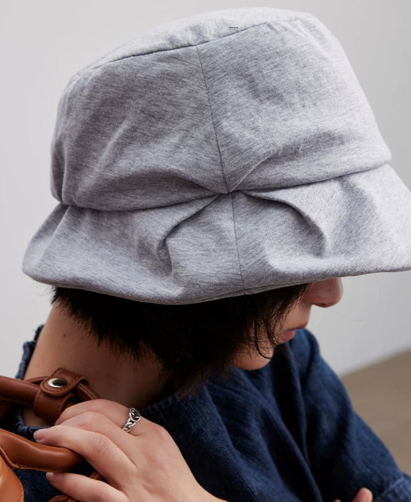 Model wearing a heather gray pleated bucket hat with the brim lowered for comfortable facial shade