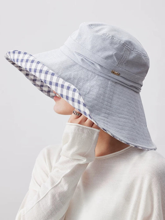 Woman wearing light blue cotton sun hat with wide brim, plaid lining, and soft foldable design