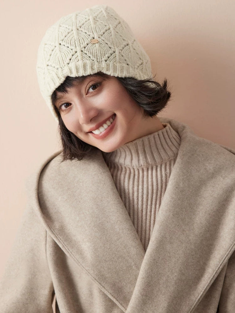 Model wearing a cream-white wool knit beanie with a beige coat and ribbed turtleneck.