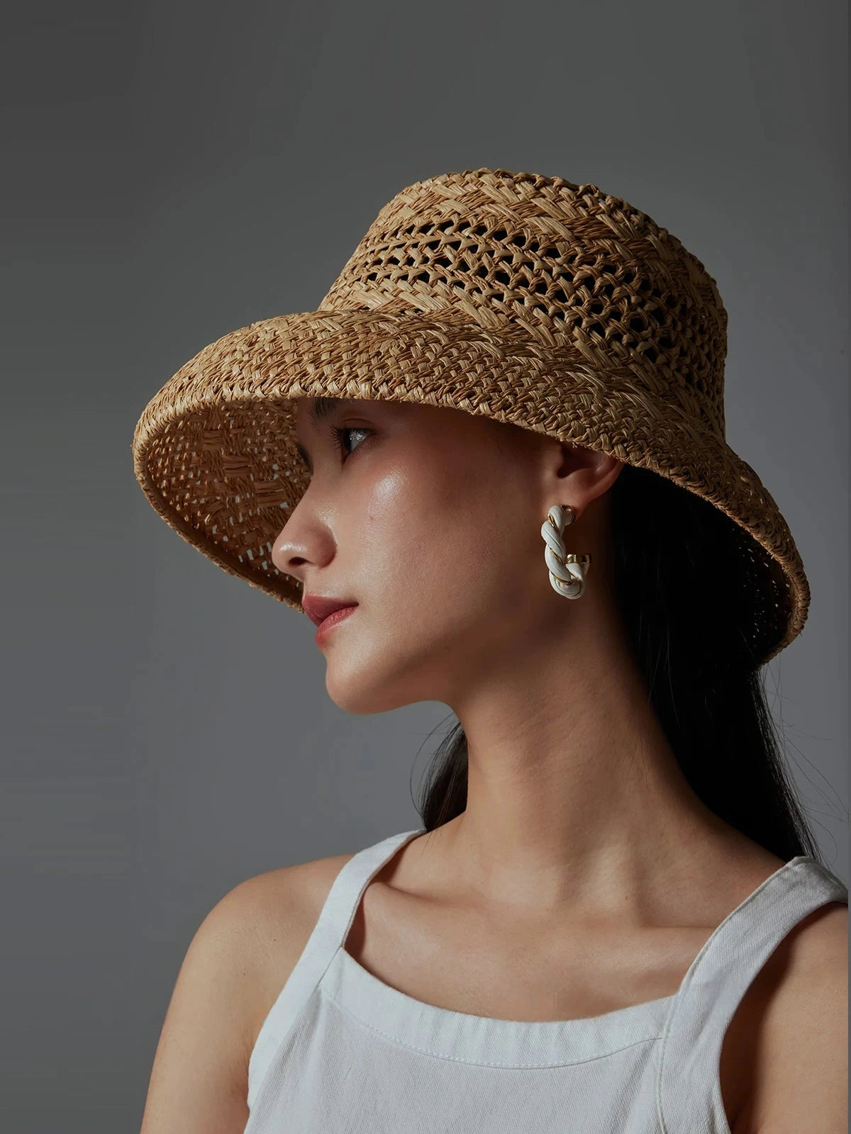 Profile view of woman in a natural raffia open-weave summer sun hat