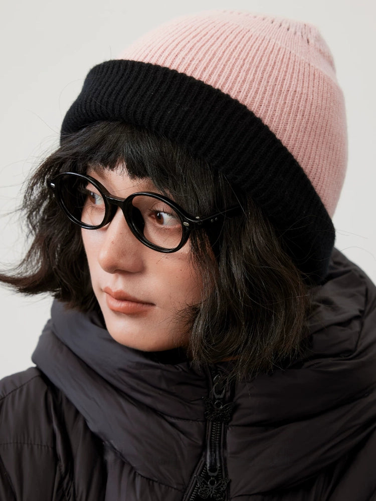 Three-quarter view of a cherry blossom pink wool beanie with a wide black fold-over cuff.
