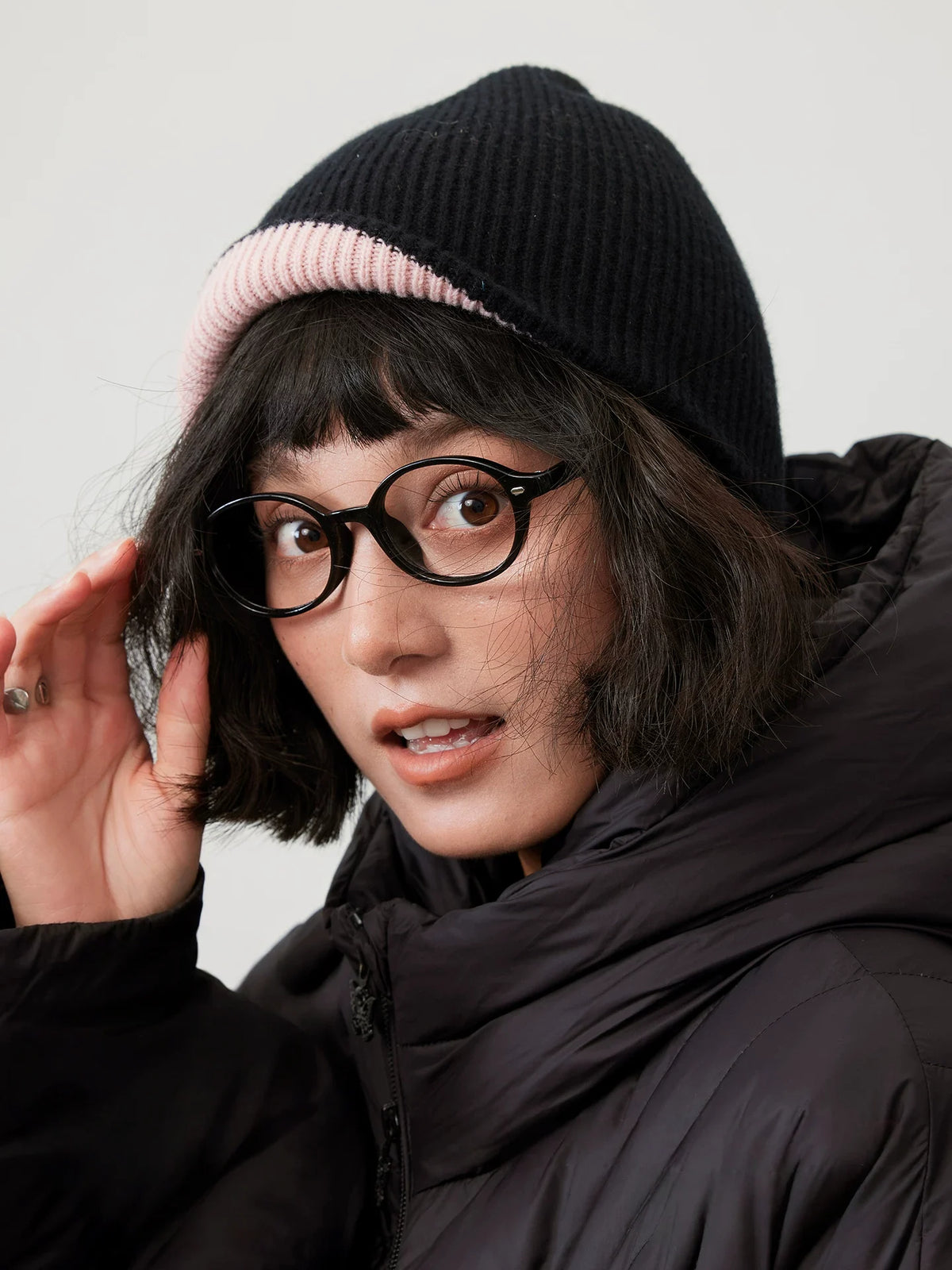 Black wool beanie with a cherry blossom pink cuff, modeled with black glasses and a puffer jacket.