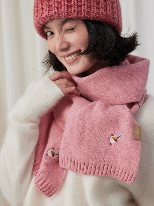 Sakura pink embroidered wool scarf wrapped close to the neck with ribbed ends crossed at the chest.