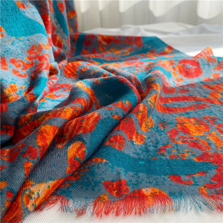 Close-up of lightweight wool scarf folds with vibrant teal, orange-red and peacock details