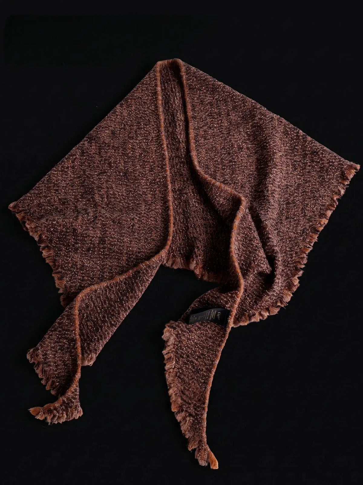 Terracotta cashmere triangle scarf laid out to show its triangular shape, textured knit and fringed edges.