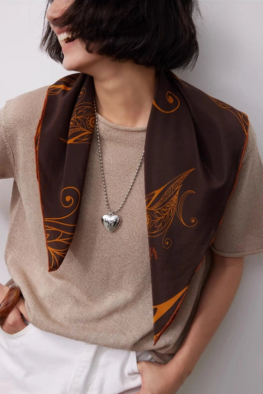 Vintage brown silk square scarf draped loosely around the neck, featuring an artistic goldfinch pattern.