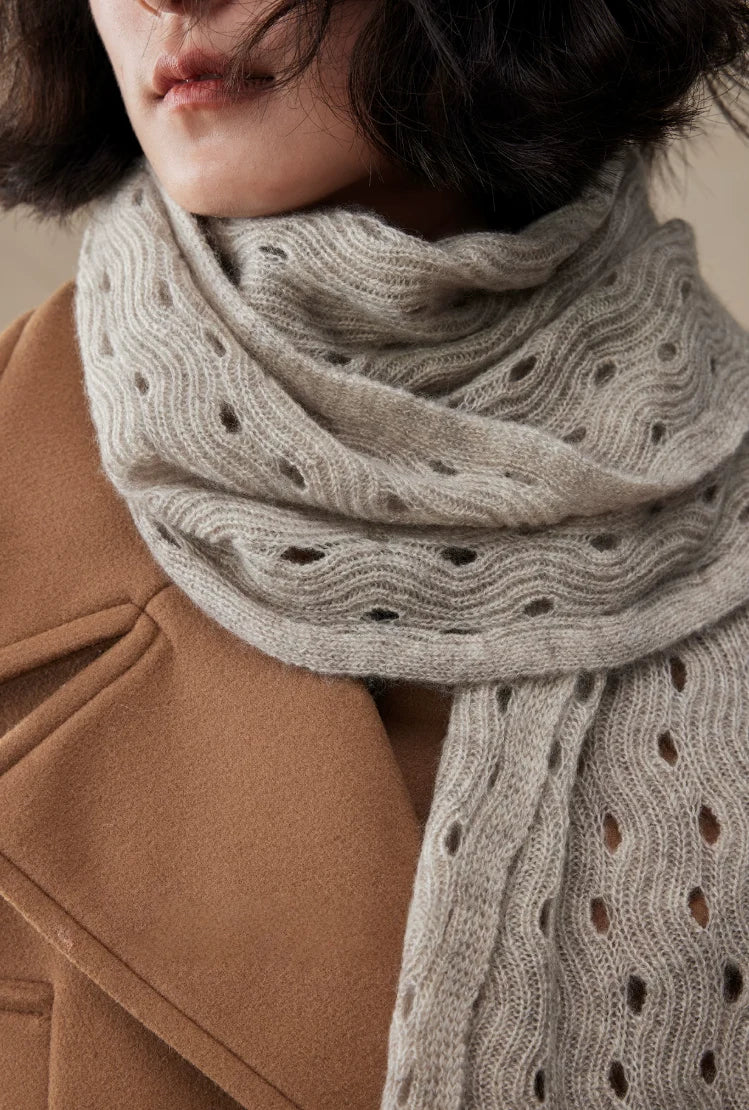 Light khaki cashmere scarf wrapped around the neck, showing layered folds and delicate openwork stitches.
