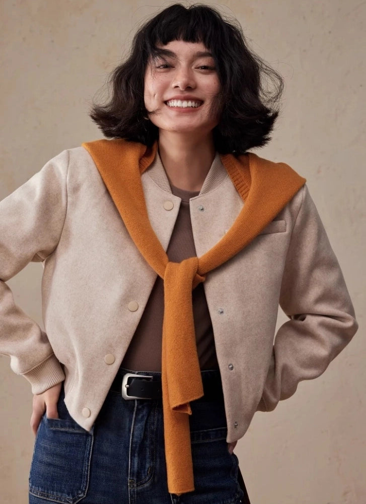Woman wearing a burnt orange wool hooded scarf draped over the shoulders with a beige jacket