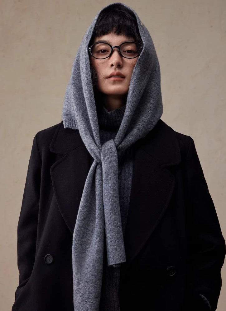 Woman wearing a dark grey wool hooded scarf tied at the neck over a black coat