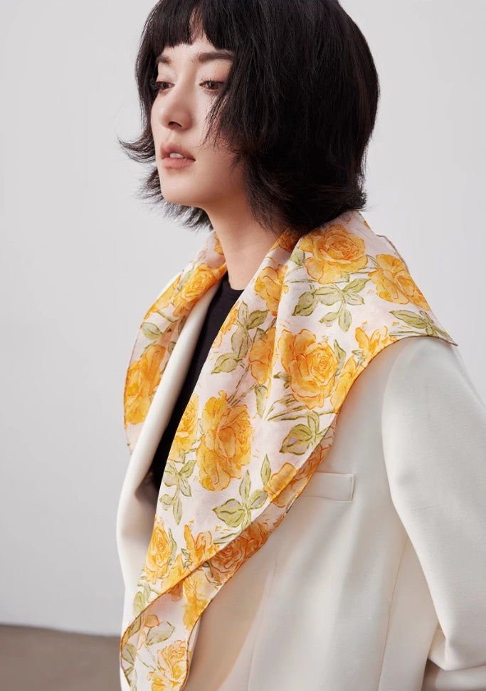 Model wearing a yellow rose print silk square scarf as a stylish hair accessory, showcasing its lightweight and breathable design.