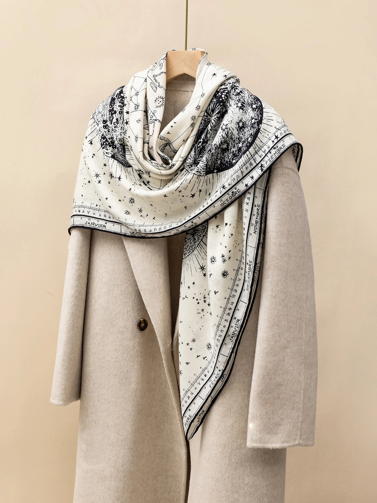 Silk Wool Square Scarf - Cosmic Star Map Print | Beige, 130*130cm, angled on coat, highlighting star and moon motifs, elegant fashion statement.