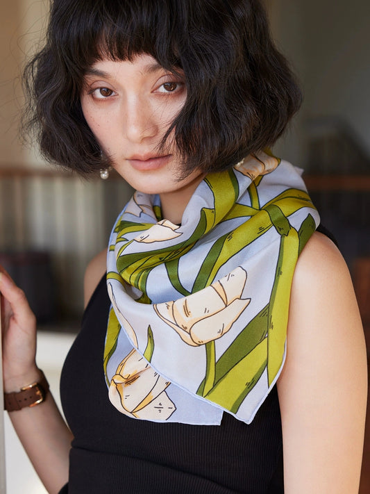 A blue tulip floral print silk square scarf made from 100% mulberry silk is displayed as a neck scarf.