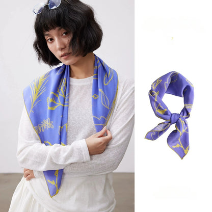 Blue botanical silk square scarf styled around the neck with matching flat lay detail