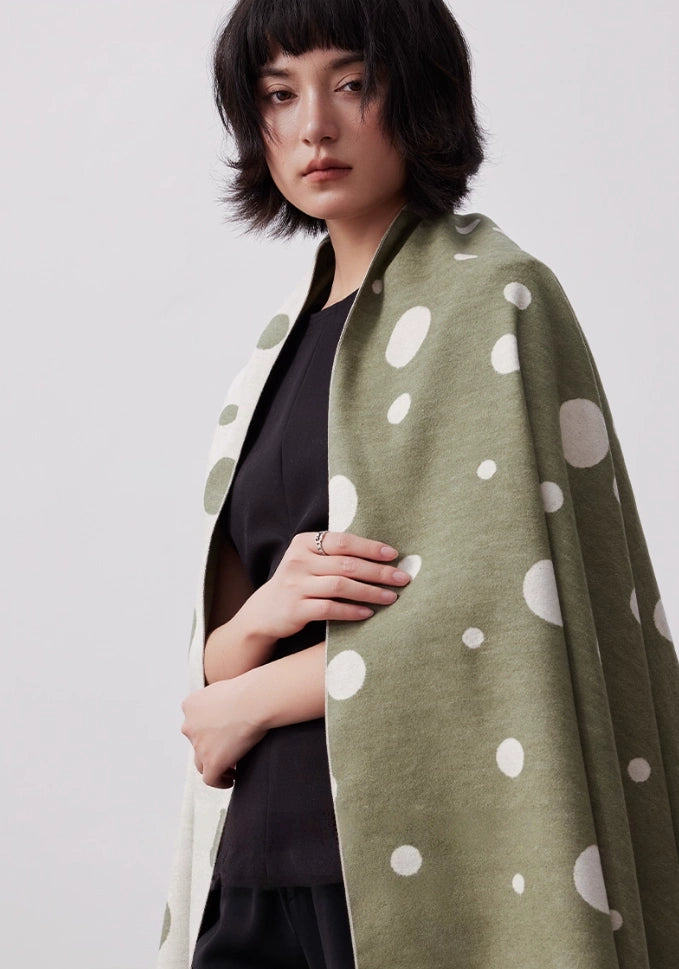 Model wearing olive green soft brushed silk scarf as a large neck wrap with artistic polka dot print
