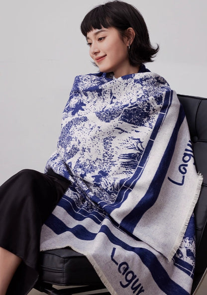 Model wrapped in a blue brushed silk scarf with abstract print, styled as a soft winter shawl