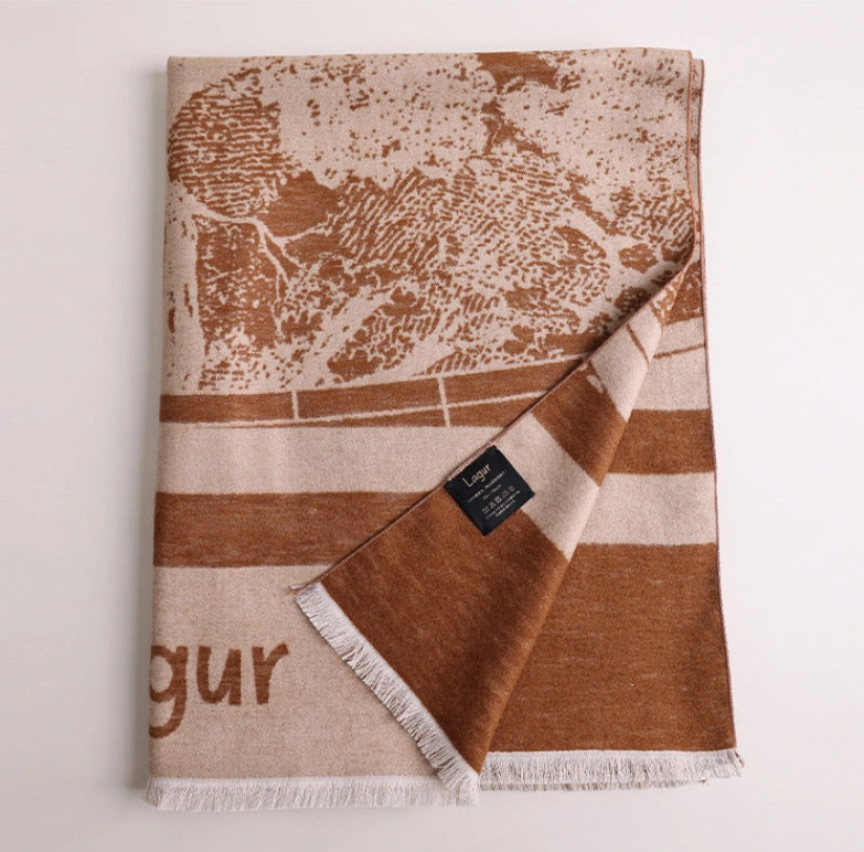 Folded brown large brushed silk scarf with artistic abstract print, soft fringed edge, and cashmere-like texture