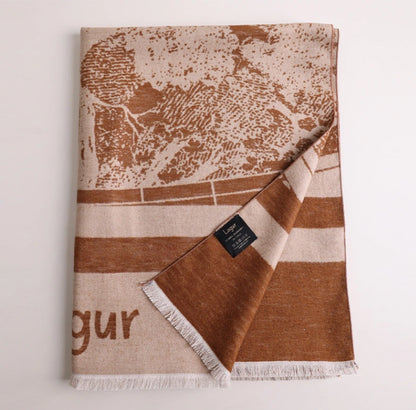 Folded brown large brushed silk scarf with artistic abstract print, soft fringed edge, and cashmere-like texture