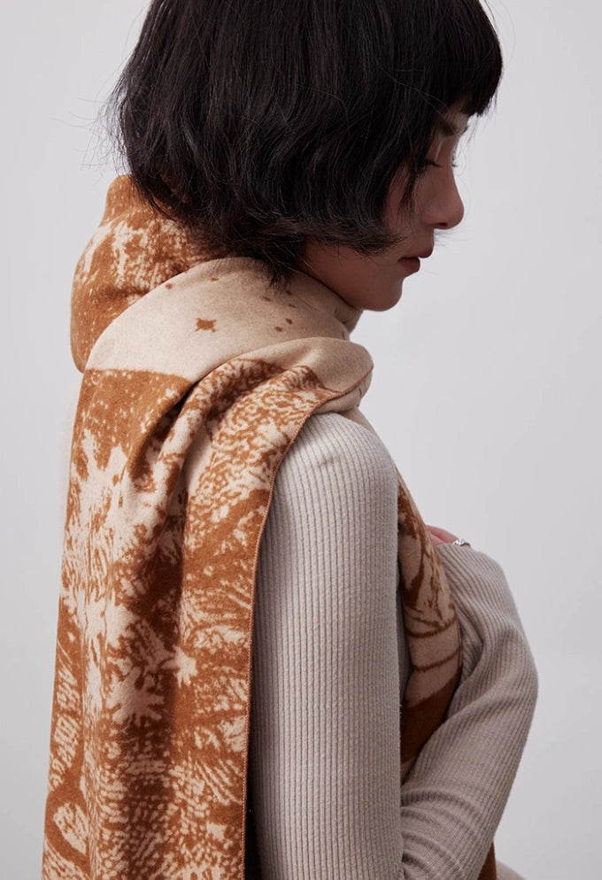 Brown large brushed silk scarf worn over the shoulder with soft cashmere-like texture and artistic winter print