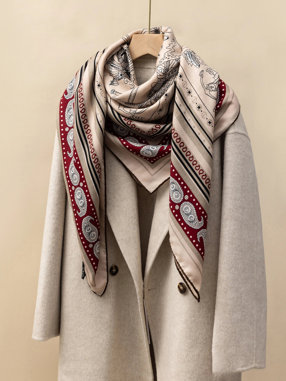 Silk wool square scarf draped over a beige coat, showcasing the luxury and versatility of this scarf.