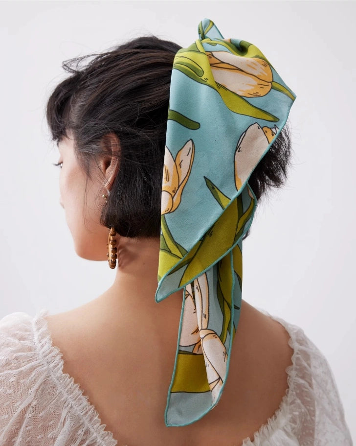 A green tulip floral printed silk square scarf made from 100% mulberry silk, shown as a hair scarf.