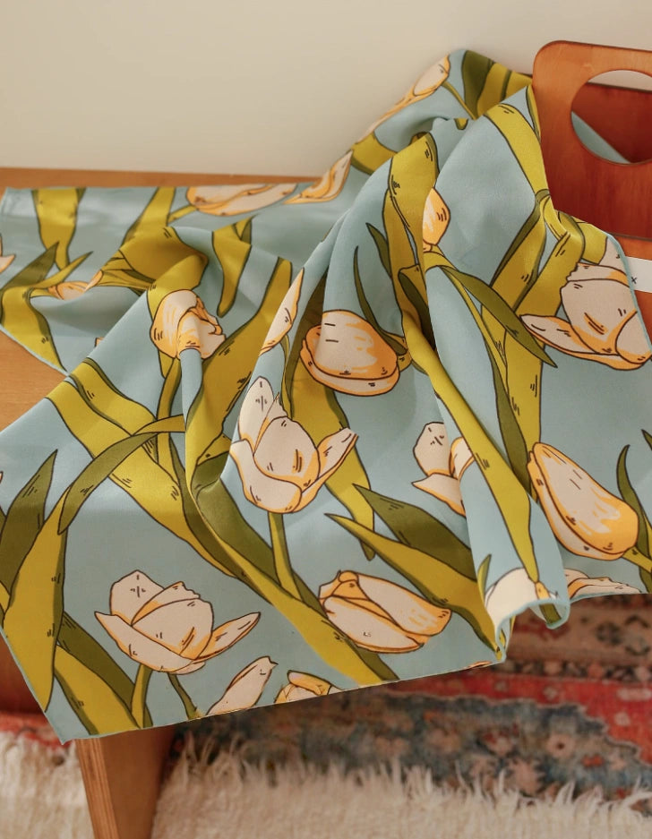 Green tulip print silk square scarf displayed on a chair to show soft drape and sheen