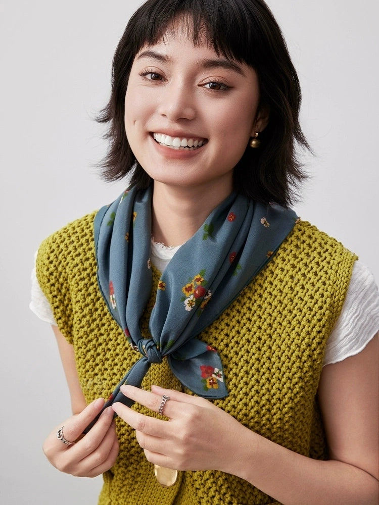 Greenish-blue floral silk square scarf styled as a neck accessory, demonstrating its elegance and versatility.