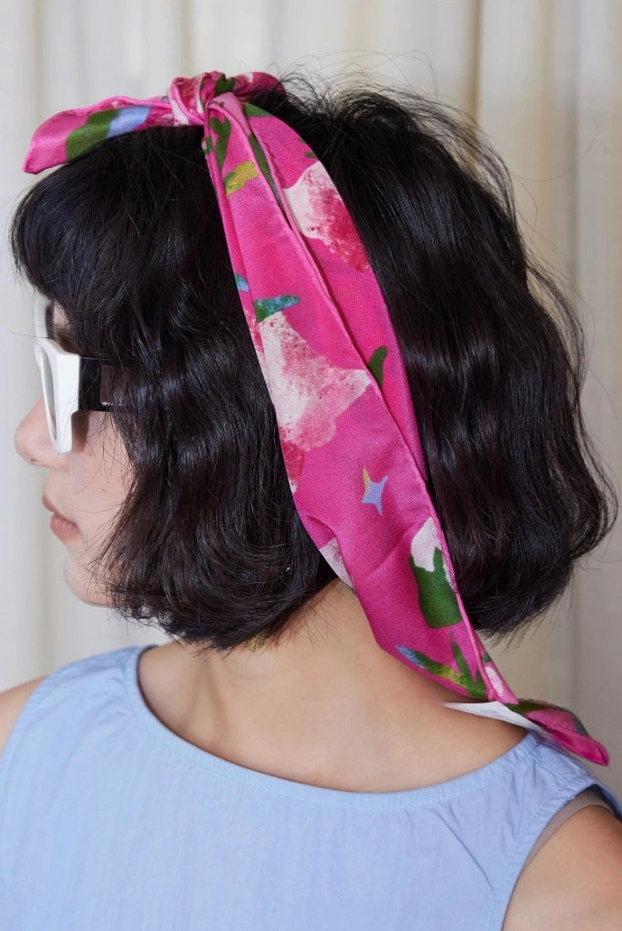 Rear view of a woman with a Berry Powder silk square scarf (63x63cm) tied as a headscarf, showcasing its floral mulberry silk design.