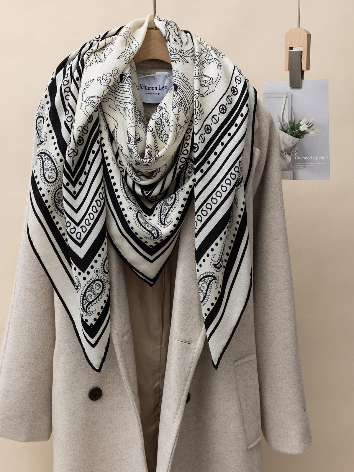 Silk wool square scarf draped over a beige coat, showcasing the luxury and versatility of this scarf.