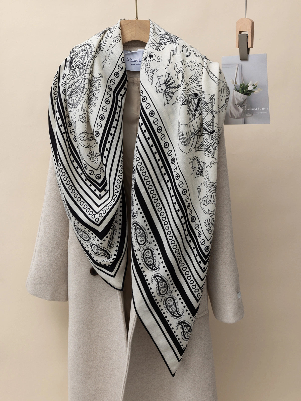 The close-up silk wool square scarf features a nautical fantasy print; draped over a beige coat, it showcases maritime and fantastical motifs.