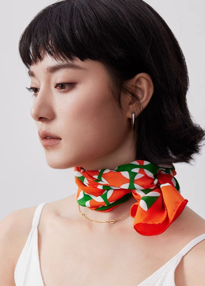Orange green geometric long silk scarf tied neatly around the neck