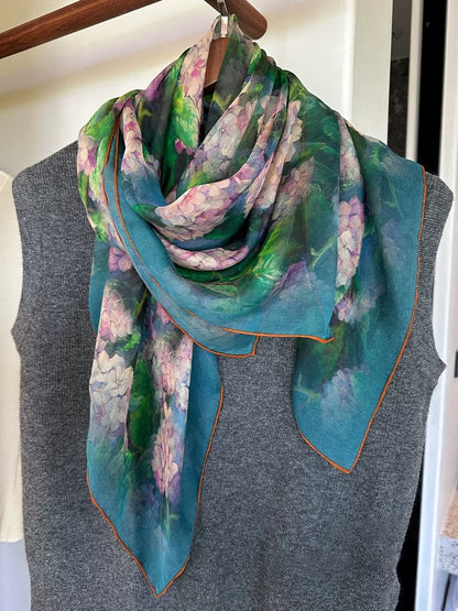 Plant-dyed floral silk square scarf draped over a grey top