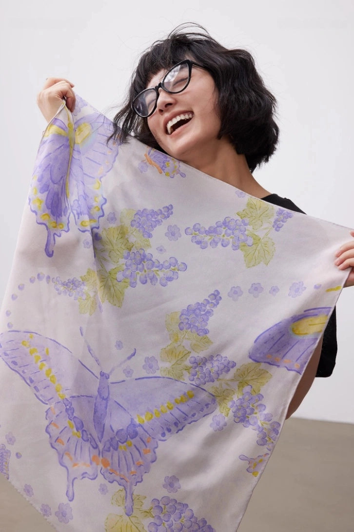 Lightweight purple butterfly print silk square scarf styled as a shoulder wrap