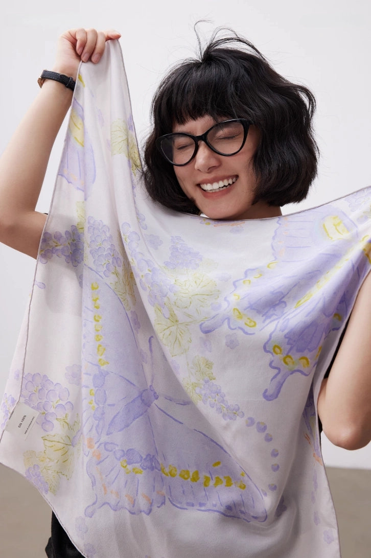 Purple butterfly mulberry silk square scarf held up to show its soft drape and sheen