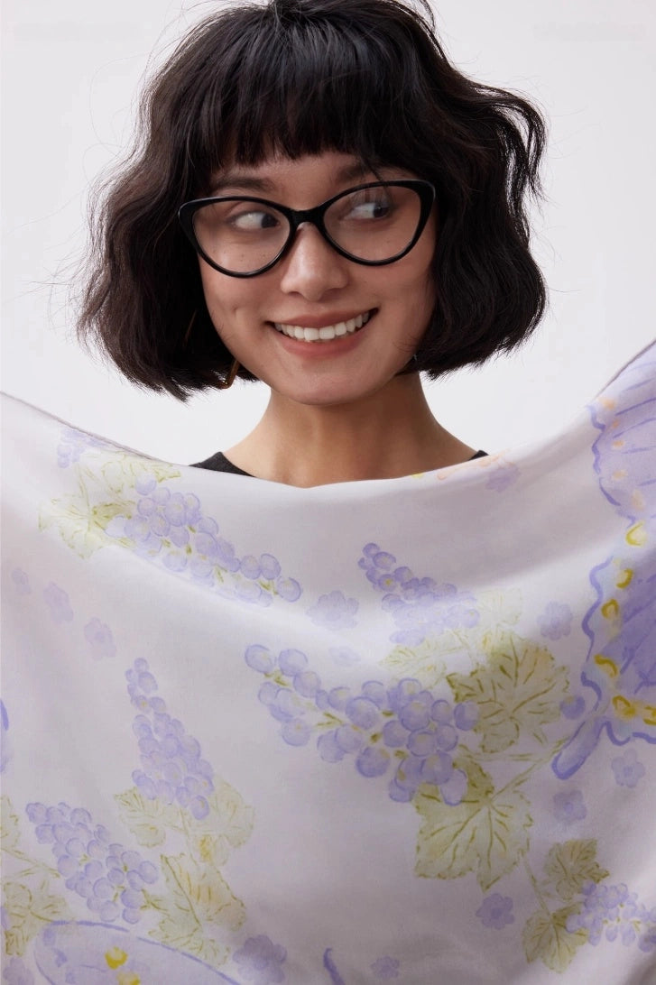 Close-up of purple butterfly print silk scarf with soft pastel floral details
