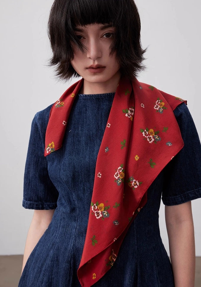 Red floral silk square scarf draped gracefully, emphasizing its smooth texture and timeless design.