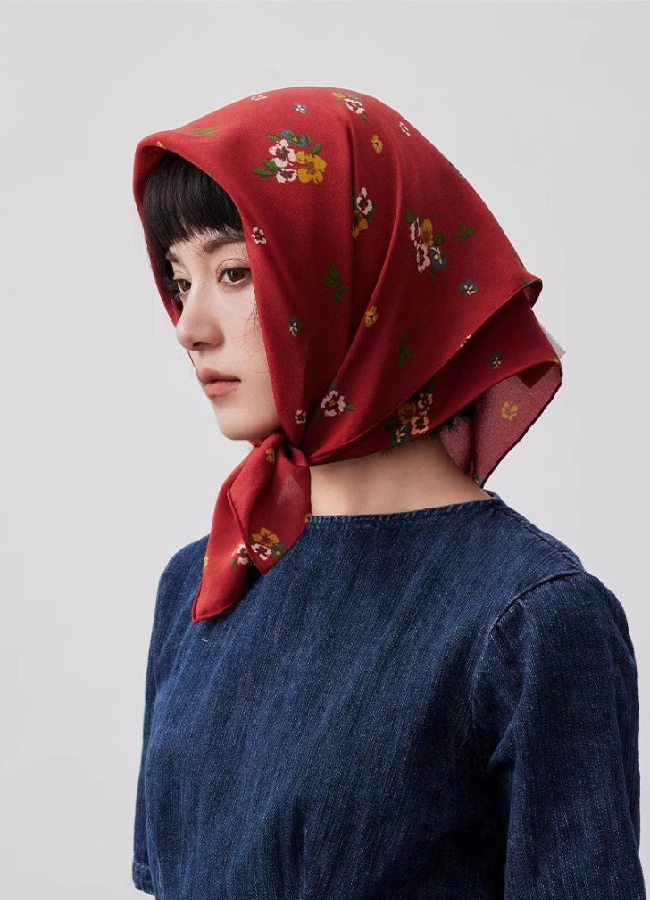 Red floral silk scarf styled as a chic headscarf, showcasing its lightweight and breathable material.