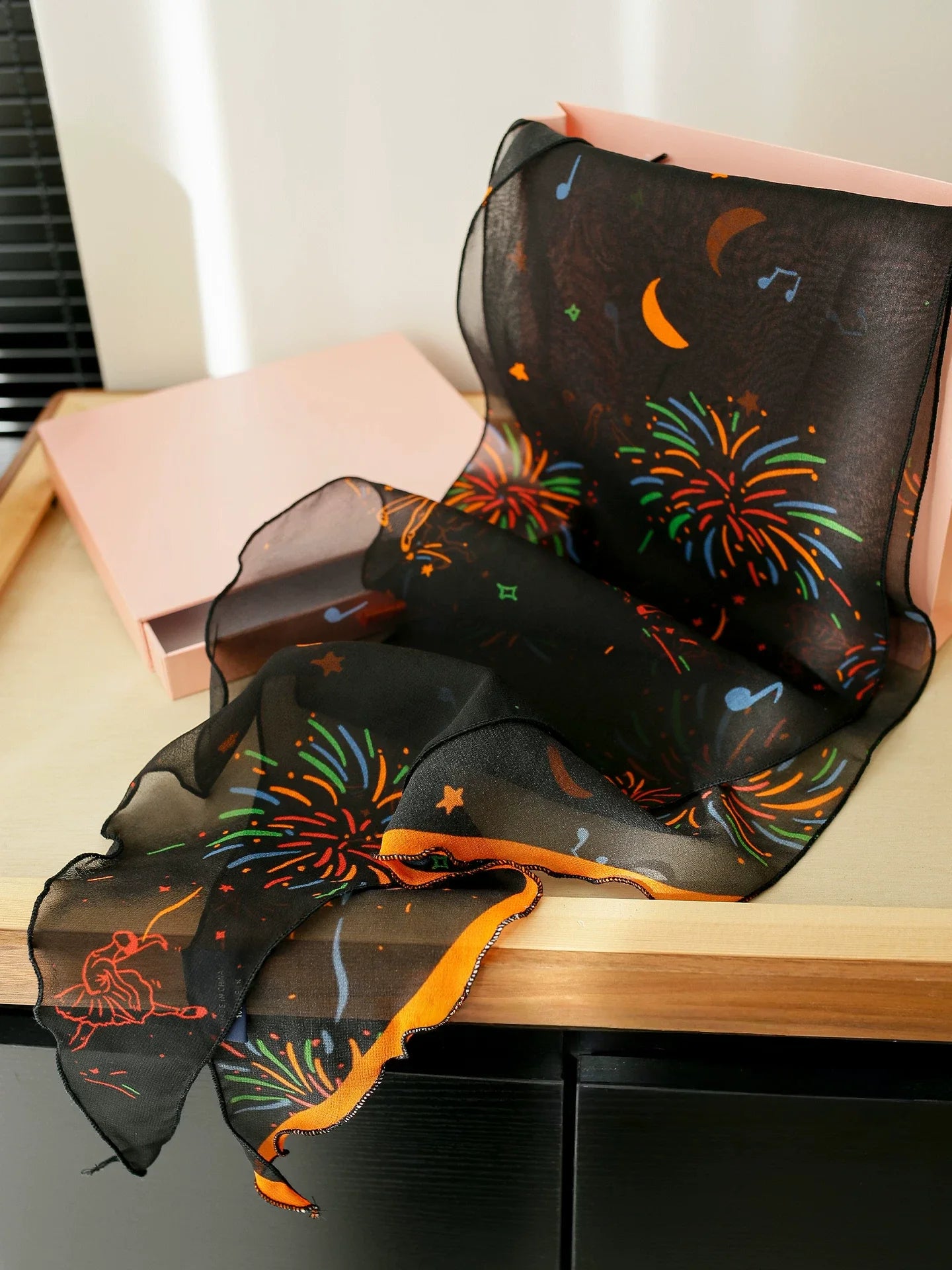 Black fireworks mulberry silk skinny scarf displayed to show its lightweight georgette texture and colorful print